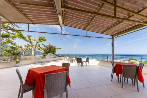 an outdoor patio with tables and chairs and the ocean at San Carlo - Terrazzo sul Mare con Ristorante e Pizzeria in Zambrone