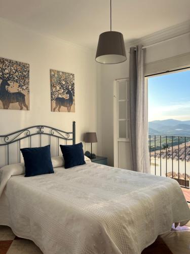 a bedroom with a bed and a large window at Casas PARAJE NATURAL in Zahara de la Sierra