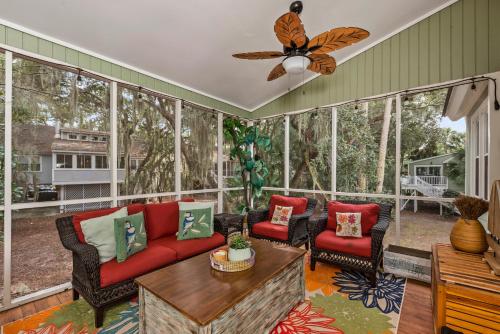 a screened in porch with a red couch and chairs at 515 Tarpon Pond Cottage in Seabrook Island