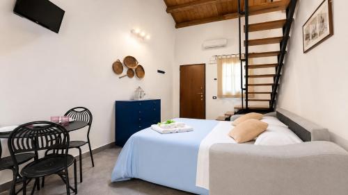 ein Schlafzimmer mit einem Bett, einem Tisch und einer Treppe in der Unterkunft Loft Bonbon in Cinisi