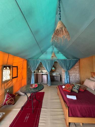 a bedroom with a bed and a table in a room at Ez-zine Glam in El Aadamna