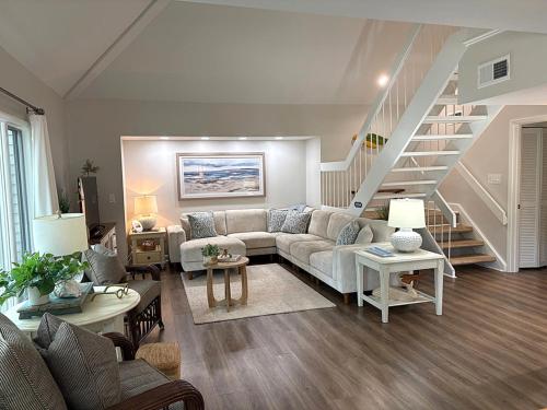 a living room with a couch and a staircase at 767 Spinnaker Beach House in Seabrook Island