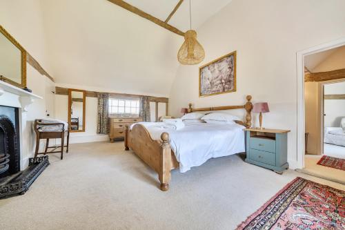 a bedroom with a large bed and a fireplace at Cutbush Farmhouse in Norwich