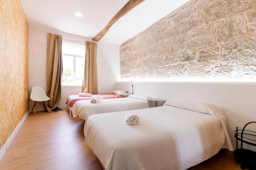 two beds in a room with a brick wall at Casa Bubela - Vía de la plata in Dozón