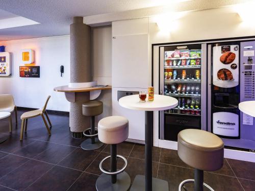 a restaurant with a refrigerator and tables and chairs at ibis budget Orange Centre in Orange