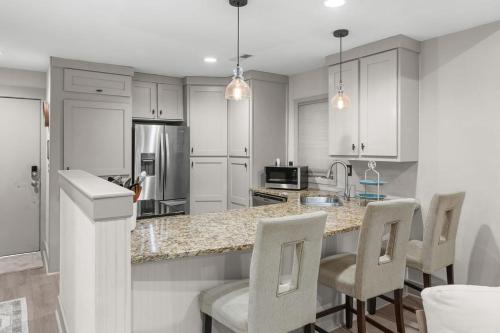 a kitchen with white cabinets and a counter with chairs at 620 Shadowwood in Seabrook Island
