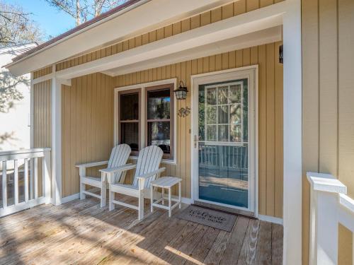 a porch with two chairs and a table on it at 545 Tarpon Pond Cottage in Seabrook Island