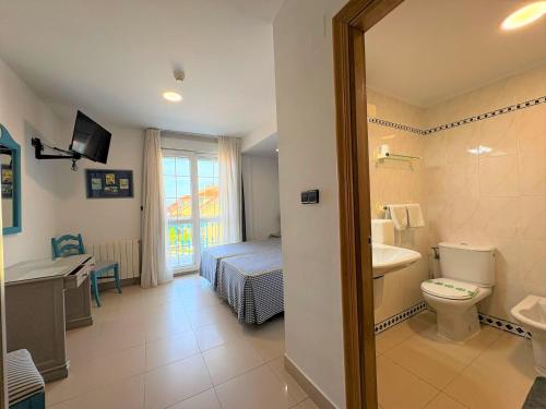 a bathroom with a toilet and a sink and a bed at Hotel Pineda Playa in Noja