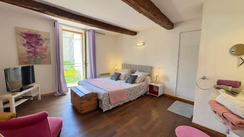 a bedroom with a bed and a tv and a couch at L'AMARILYS chambre d'hôte au coeur du village, terrasse avec vue sur le château in Châteauneuf-du-Pape