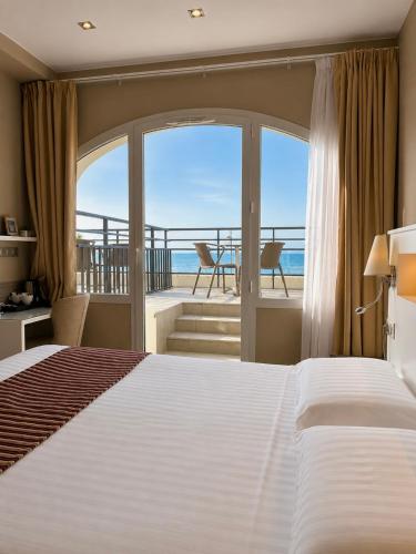 a bedroom with a bed and a view of the ocean at Hôtel Valencia in Hendaye