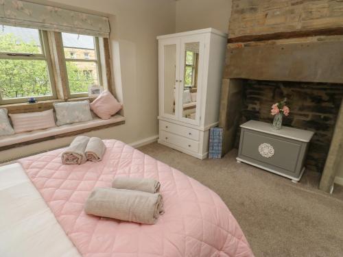 a pink bedroom with a large pink bed and a fireplace at Riverview Cottage in Holmfirth