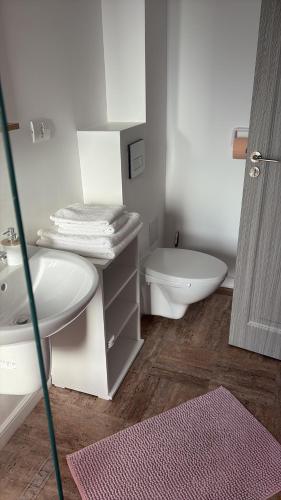 a white bathroom with a toilet and a sink at Vila Siena in Sulina