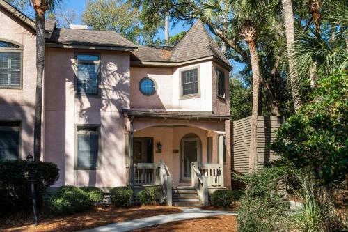a pink house with a porch and palm trees at 2504 Chateau by the Green in Seabrook Island