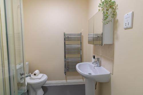 a white bathroom with a toilet and a sink at Great offers on Long Stays!! LaLuNa Apartments in Gateshead