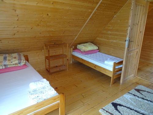 a room with two beds in a log cabin at Domek Bieszczady Wolkowyja 2 nad Solina in Wołkowyja