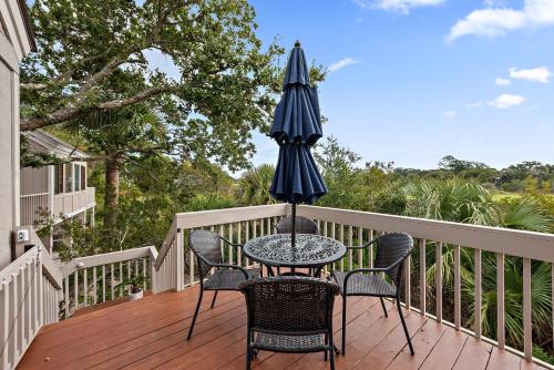 a table and chairs on a deck with an umbrella at 818 Treeloft Cottage in Seabrook Island