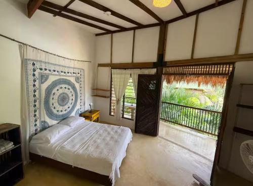 a bedroom with a large bed and a balcony at Hostal El Bohío in Palomino