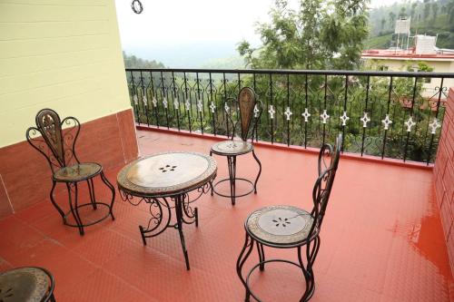 four chairs and tables on a balcony with a view at sunshine retreat in Coonoor