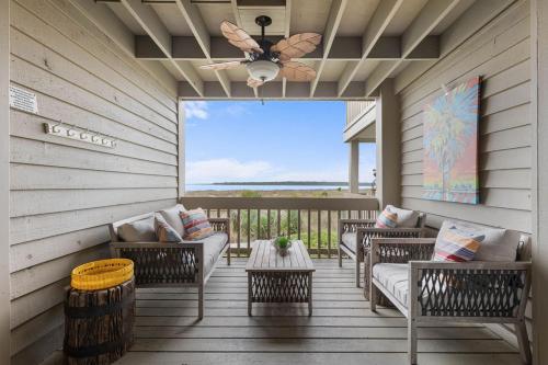 a screened in porch with chairs and a ceiling fan at 1327 Pelican Watch Villa in Seabrook Island