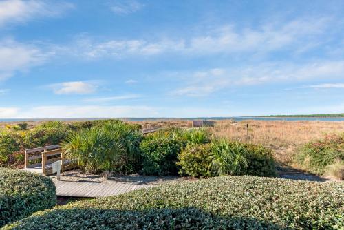 a wooden walkway with a view of a field at 1307 Pelican Watch Villa in Seabrook Island