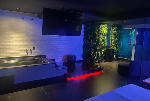 a living room with a tv on a wall at Anonimato Hotel in Santos