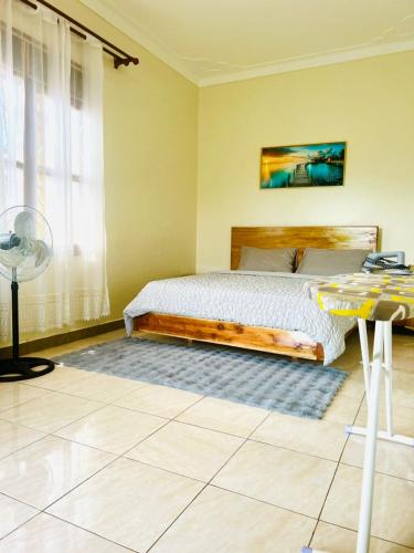 a bedroom with a bed and a table and a window at Robchen homes in Entebbe