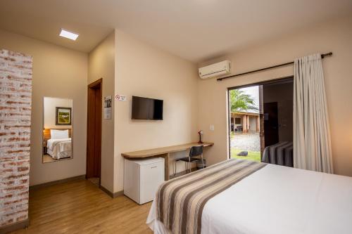 a bedroom with a bed and a desk and a tv at Rancho das Pedras Itaberá in Itaberá