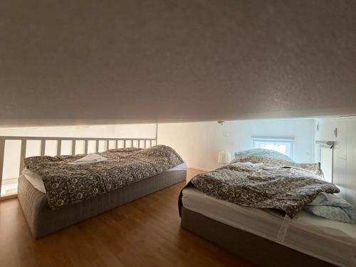 two beds sitting in a room with at Cozy Cottage in Södertälje