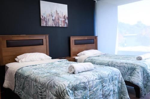 a bedroom with two beds with towels on them at Apart Hotel Castellon 176 in Concepción