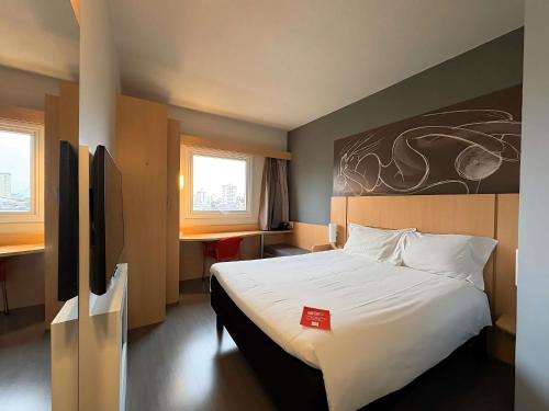 a hotel room with a bed with a red card on it at ibis Jundiai Shopping in Jundiaí