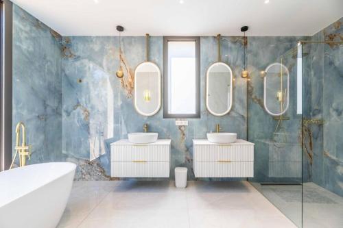 a bathroom with two sinks and two mirrors at Hotel Monte Sereno in Zonza