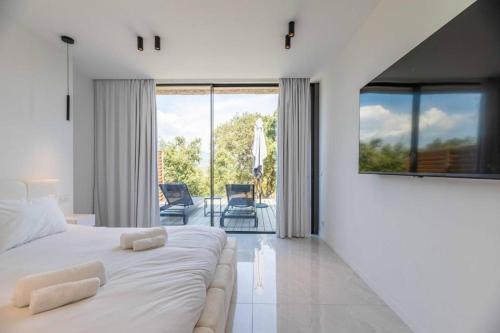 a white bedroom with a large bed and a balcony at Hotel Monte Sereno in Zonza