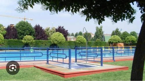 a swimming pool with blue railing in a park at Hostal Dobe in Benavides