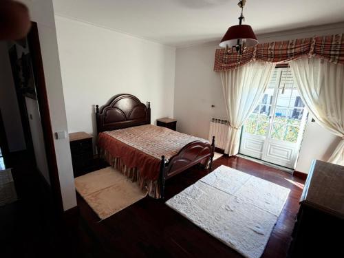 a bedroom with a bed and a large window at Vio's Home in Serra de El-Rei