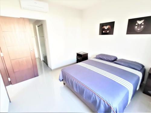 a bedroom with a blue bed in a white room at Mi casa, moderna B in Vila El Carmen