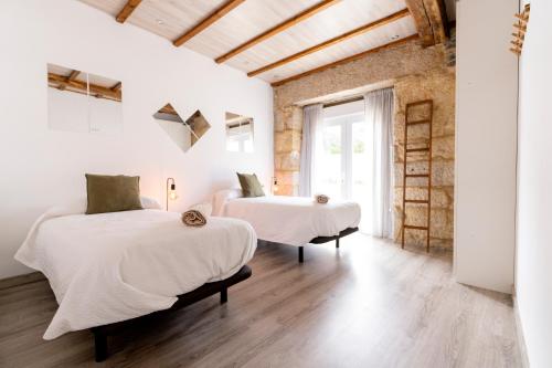 two beds in a room with white walls and wooden floors at Casa Bubela, O Castro de Dozón. in Dozón