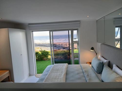a bedroom with a bed and a large window at Hermanus Oceanbay View in Hermanus
