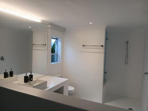 a white bathroom with a sink and a mirror at Hermanus Oceanbay View in Hermanus