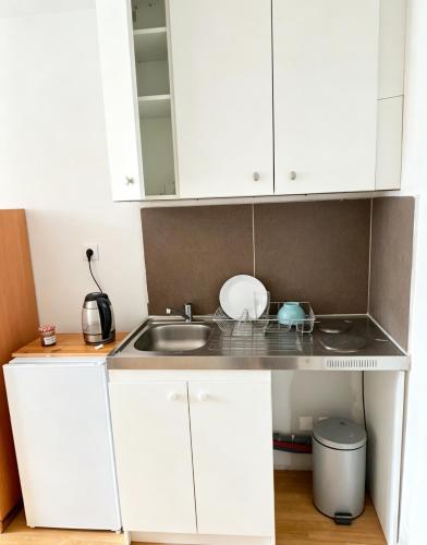 a small kitchen with white cabinets and a sink at Studio Maisons-Alfort in Maisons-Alfort