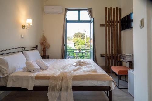 ein Schlafzimmer mit einem Bett mit weißer Bettwäsche und einem Fenster in der Unterkunft Orfeas Hotel in Mytilini