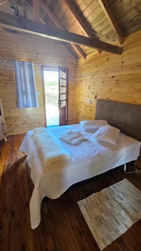 a bedroom with a large bed in a wooden room at Cabana Família Lima in Urubici