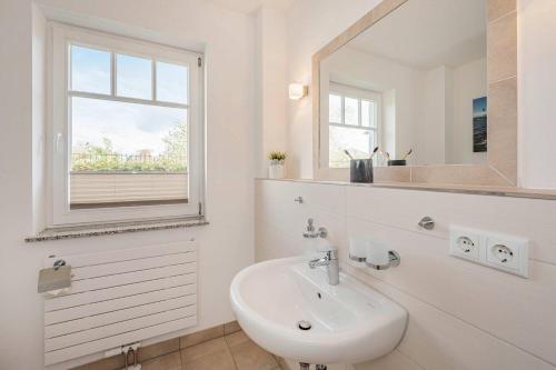 a white bathroom with a sink and a mirror at Ferienwohnung Haffblick in Kamminke