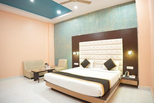 a bedroom with a bed and a chair and a table at Hotel Vishnu Vilas in Rewa