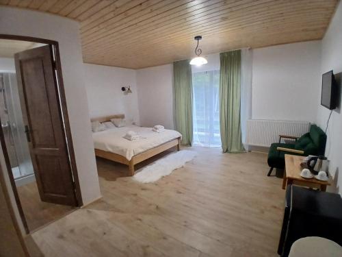 a room with a bed and a couch and a window at Hanul Ibăștean in Brădeţelu