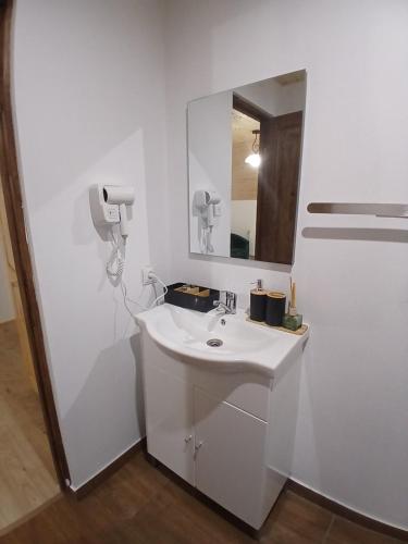 a white bathroom with a sink and a mirror at Hanul Ibăștean in Brădeţelu