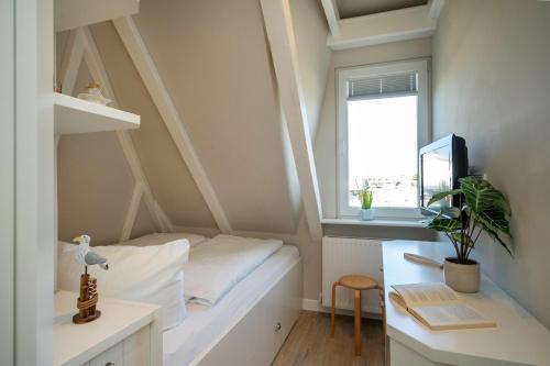 a small room with a bed and a desk and a window at Silwai OG in Westerland