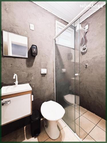 a bathroom with a toilet and a glass shower at Nônames Urban Hostel in Florianópolis