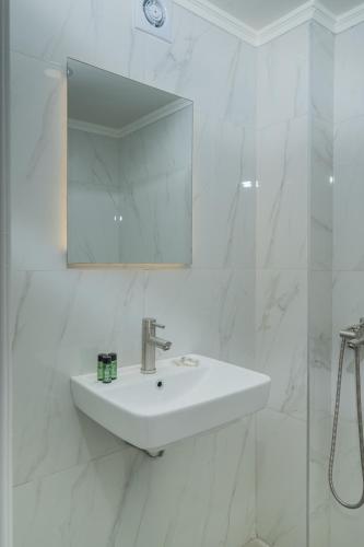 ein weißes Badezimmer mit Waschbecken und Spiegel in der Unterkunft Orfeas Hotel in Mytilini