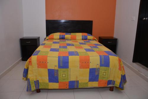 a bed with a colorful comforter in a room at Hotel Posada Aurorita in Villahermosa