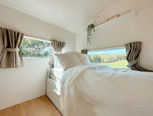 a white bedroom with a bed and a window at SOL Glamping at Khao yai in Ban Nong Makha
